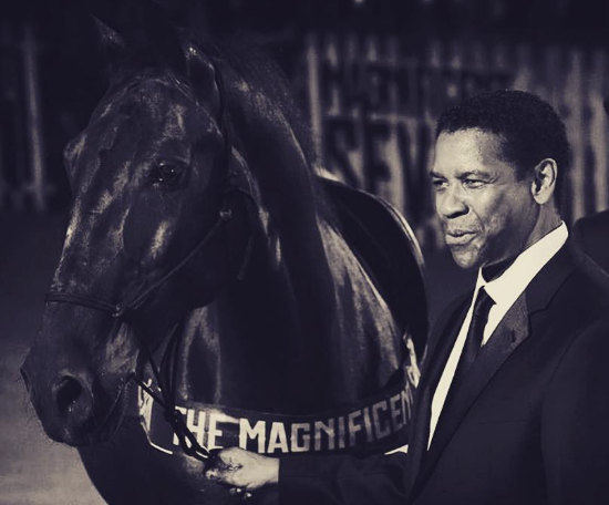 Denzel Washington accanto a un cavallo scuro con la scritta The Magnificent Seven, fotografia in bianco e nero