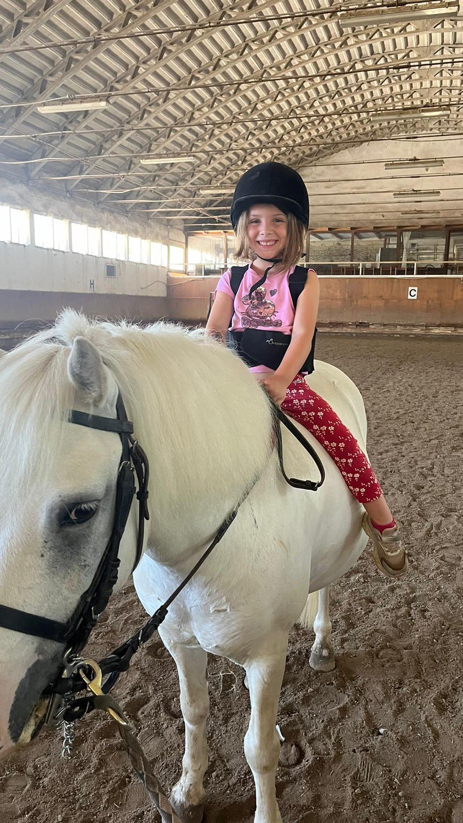 Bambina sorridente a cavallo nel maneggio coperto